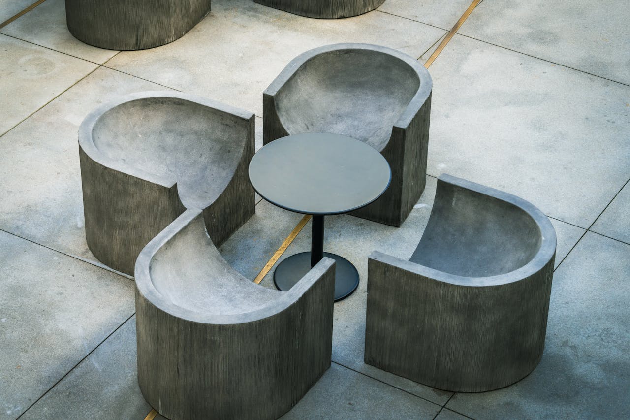 Stylish concrete furniture set with chairs and table on a tiled outdoor patio in Los Angeles.
